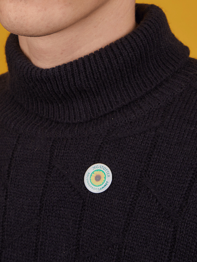 mand i sort trøje med rundt solsikke badge