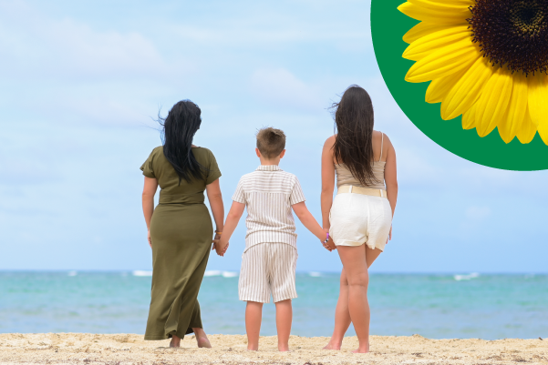 Photo of a mum, young boy and and teenage daughter holding hands looking out to sea.