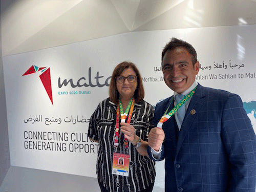 Photo of man and woman in front of wall with logo and text saying inclusion