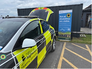Traffic Officer vehicle beside a sign reading 'Not all disabilities are visible' with the Sunflower symbol