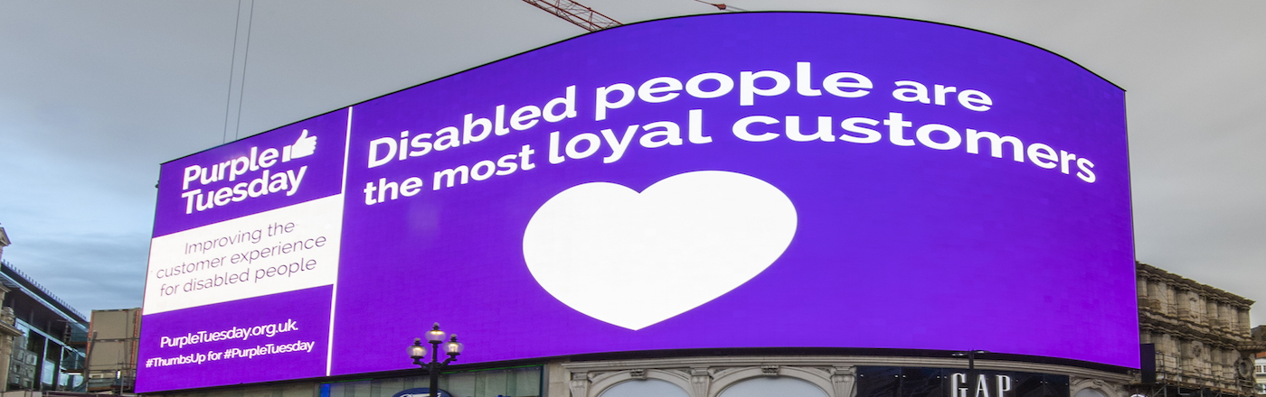 Piccadilly Circus advertising board in Purple. Reads: Disabled People are the most loyal customers