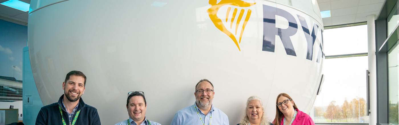 Five members of the HDS and Ryan Air team in front of a Ryan air plane that appears to be inside