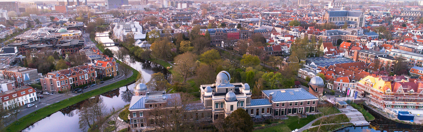 An aerial photo of the city of Leiden. Buildings and a river can be seen.
