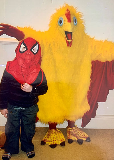 An adult and child in fancy dress. The adult is dressed as big bird from sesame street and the child is dressed as spider man. 