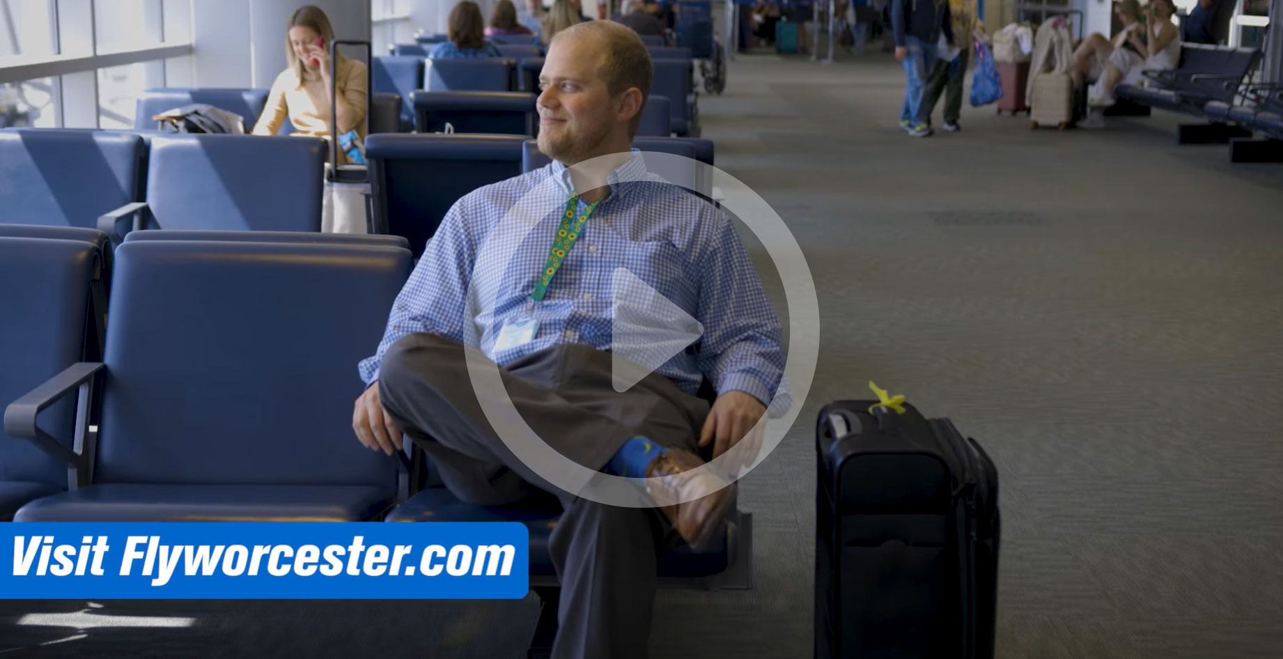 Man sitting in airport wearing green Sunflower lanyard